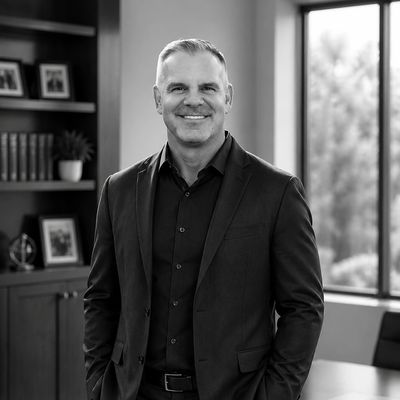 Confident man in a suit standing in a modern office with a smile.