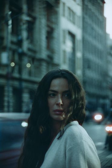 Mujer de cabello largo en ciudad al anochecer.