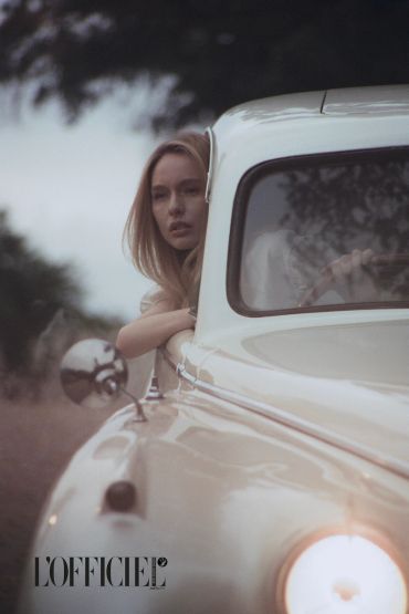 Mujer mirando desde la ventana de un coche clásico.
