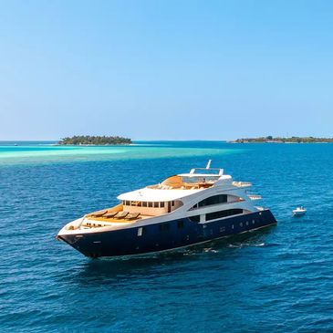 Luxury yacht sailing on clear blue tropical waters near small islands.
