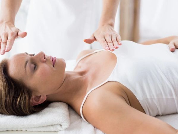 client laying on their back with practitioner waving hands just above their body