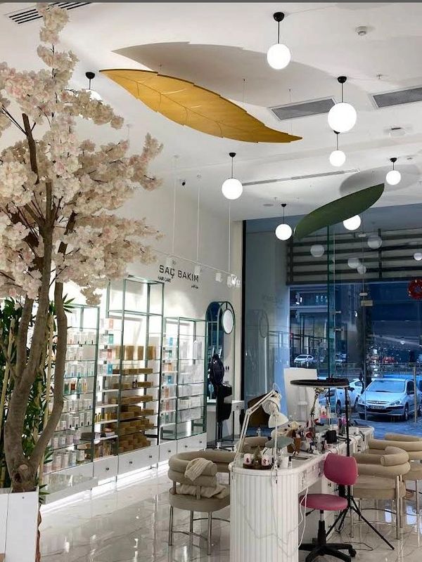 Modern salon interior with decorative plants and hanging leaf lights.