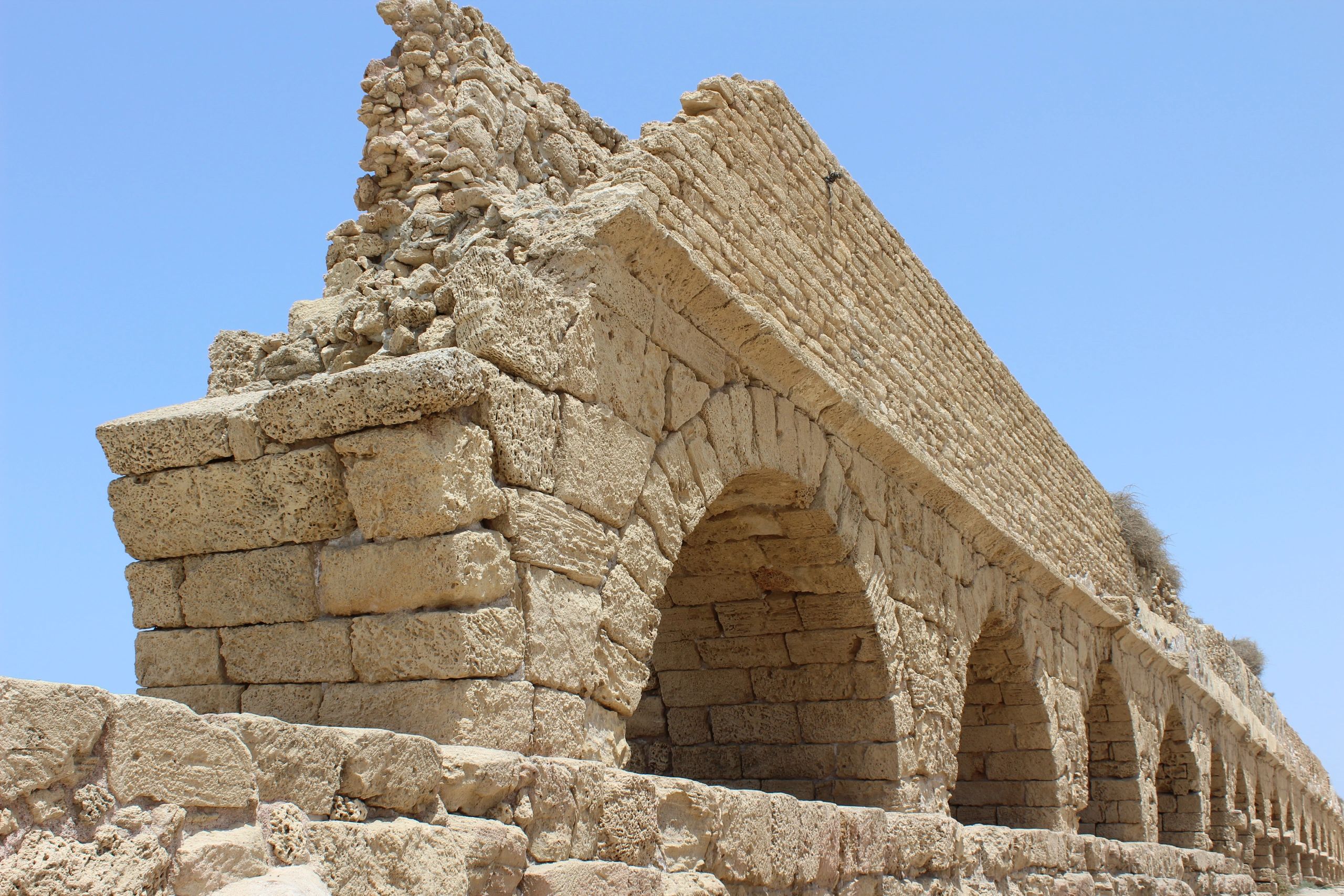 Ancient stone arch structure against a clear blue sky.
