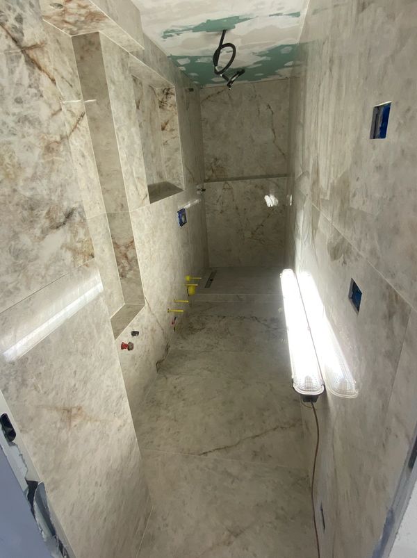 Bathroom under construction with marble walls and ceiling lights installed.