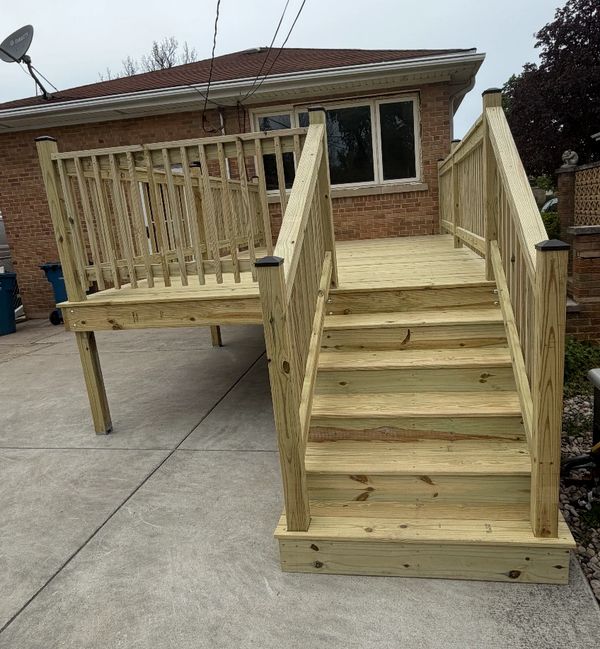 Newly built wooden deck with stairs attached to a brick house.