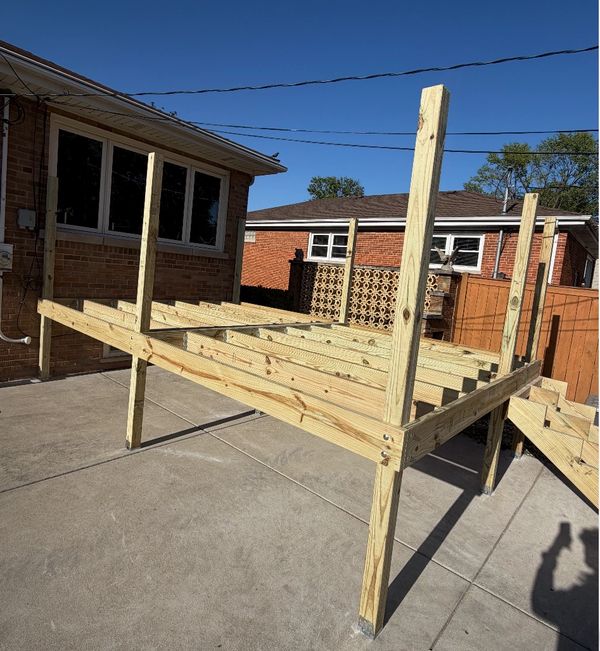 Wooden frame structure being built outdoors on a concrete surface.