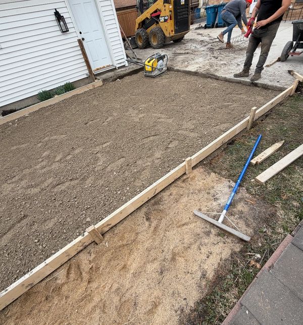 Construction site with fresh gravel and workers preparing a foundation.