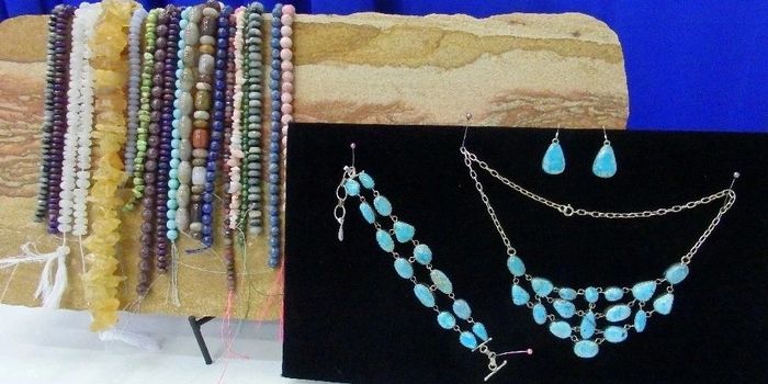 several bead and rock bracelets on wooden stand with  turquoise jewelry set on black