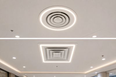 Modern ceiling with circular and square recessed lights and air vents.