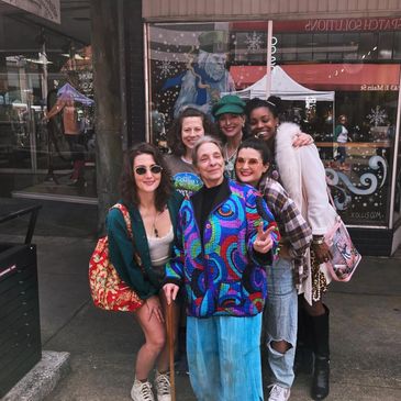 Five friends posing happily outdoors in colorful and casual outfits.