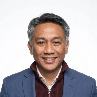 Smiling man in business attire against a plain white background.