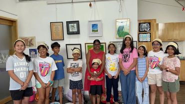 A group of children and an adult standing indoors, smiling for a photo.
