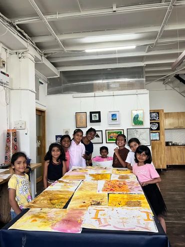 A group of children showcasing their colorful artwork in a bright room.