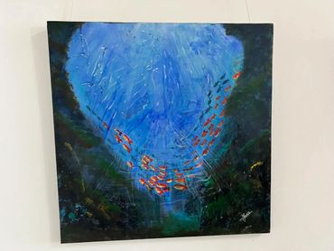 Underwater scene with a school of orange fish swimming in deep blue water.