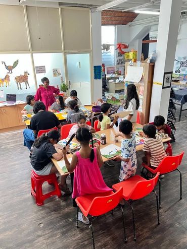 Children and adults engaged in a classroom activity around tables.