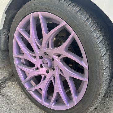 Car wheel with a unique purple alloy rim design.