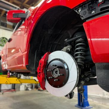 Close-up of a red car's brake system with new rotor and caliper.