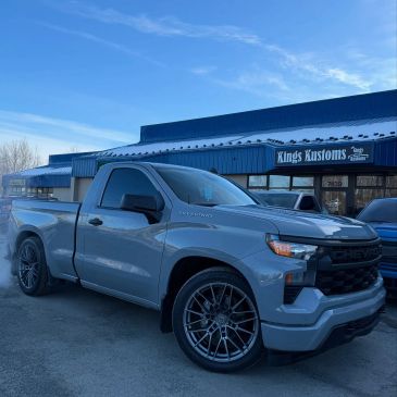 Gray Chevrolet pickup truck with custom wheels parked in front of Kings Kustoms.