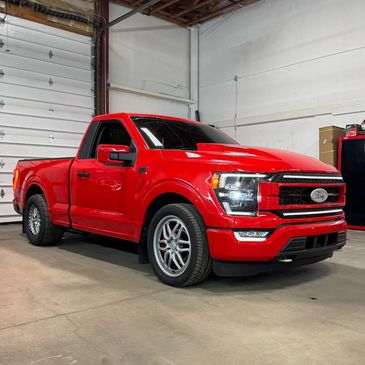 A shiny red pickup truck parked inside a garage.