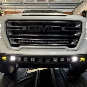 Front grille of a white GMC truck with LED light bars installed.