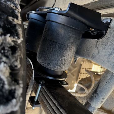 Close-up of a black air suspension bag mounted on a vehicle's leaf spring.