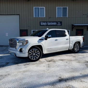 White luxury pickup truck parked outside a custom automotive shop.