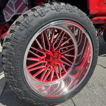 Close-up of a red and chrome custom car wheel with rugged tire.