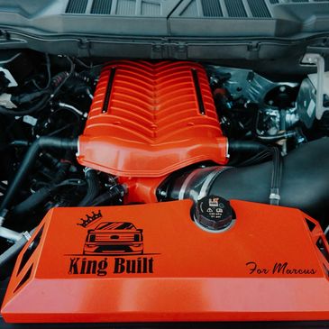 Bright orange custom engine cover with "King Built" and car graphic.