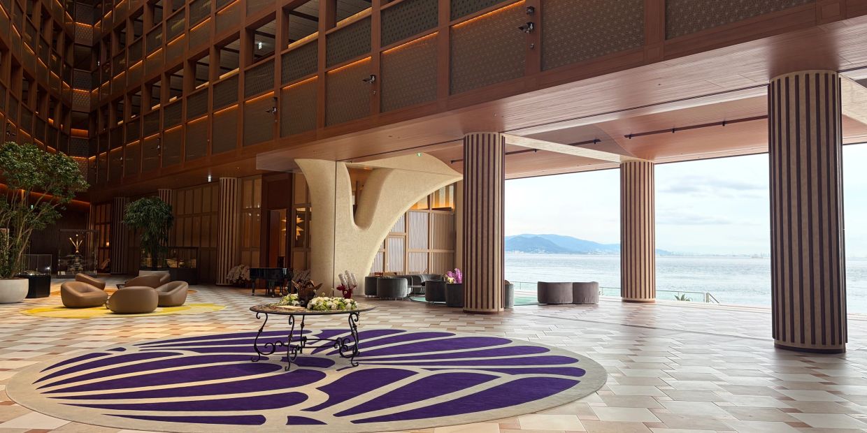 Spacious hotel lobby with sea view and modern decor.