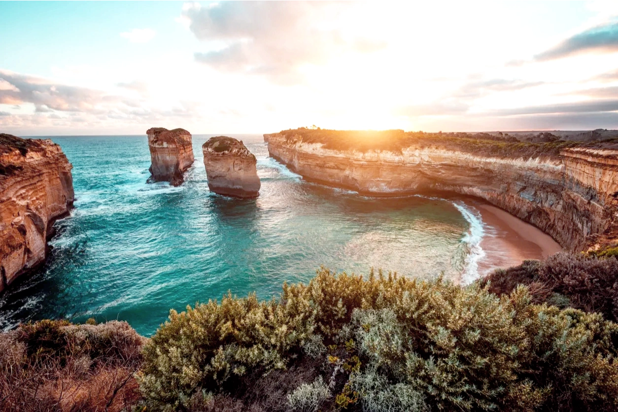 A photo of rocky shore line with some greens in the sunrise painting the sky golden  