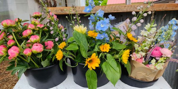 Colorful floral bouquets in black containers on a white table.