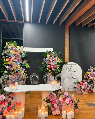 Elegant floral wedding setup with candles and clear chairs.