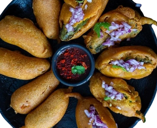 Plate of crispy fried snacks with onion garnish and a spicy red chutney dip.