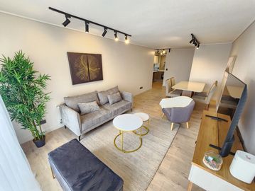 Sala moderna con sofá, mesa de centro y televisor.