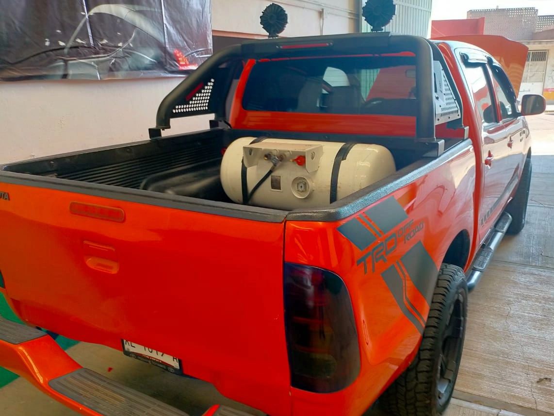 Orange Toyota pickup truck with a gas tank installed in the bed.
