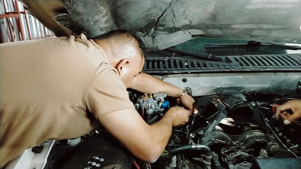 A man working on a car engine under the hood.