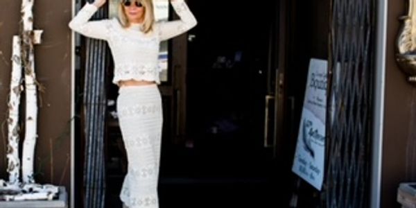 Woman in white outfit posing outside a building.