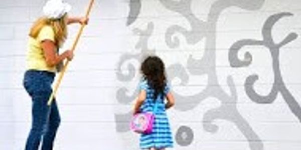 Woman and child painting a mural together.