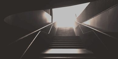 An exit from a dark underground station to the light in the street above. 