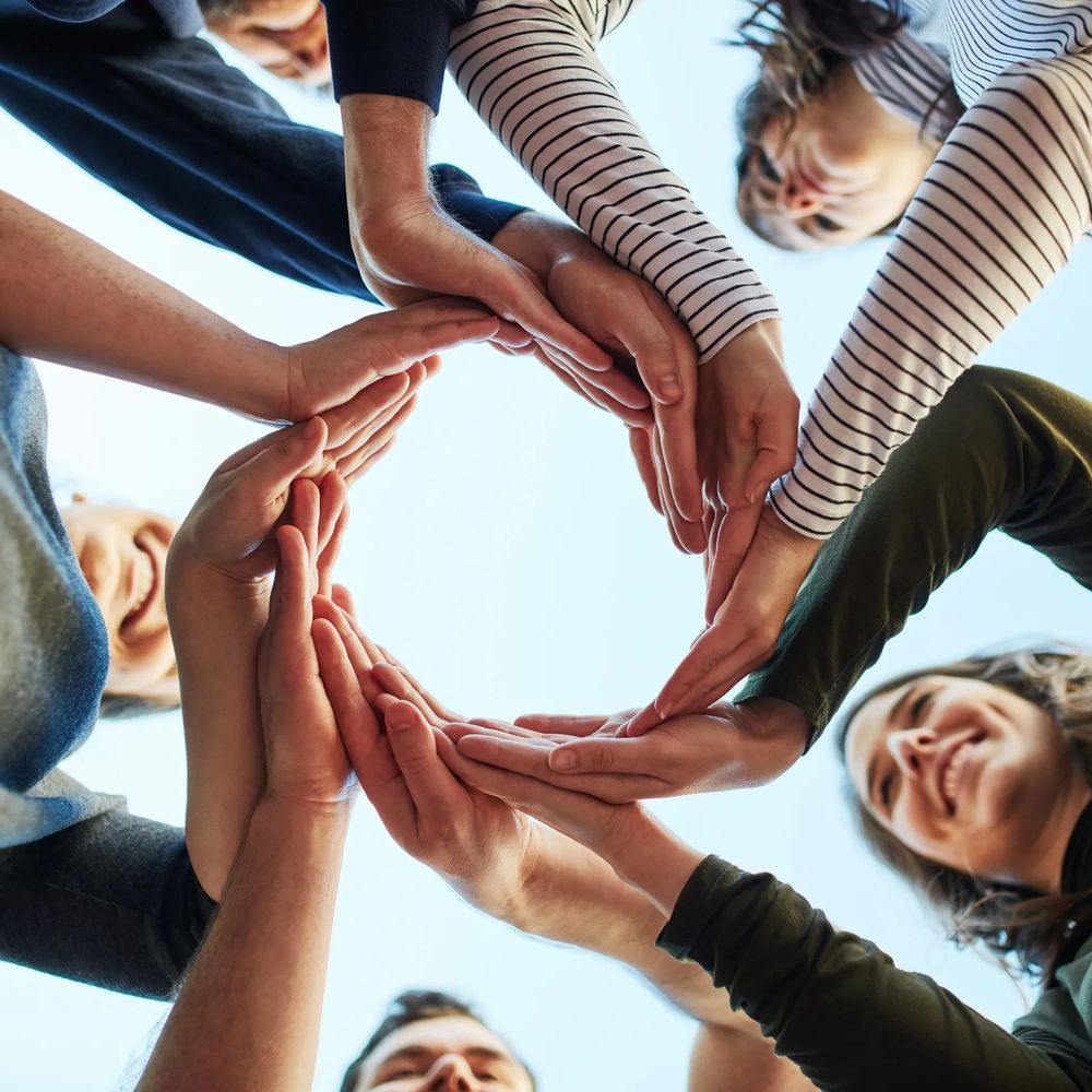People forming a circle with their hands, symbolizing unity and teamwork.