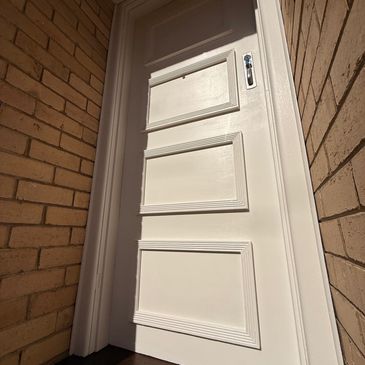 New four panel timber door hung in a brick opening by Pixi Builds carpenters, Melbourne