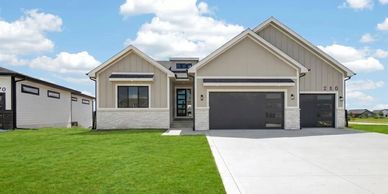 Modern single-story house with a large driveway and green lawn.