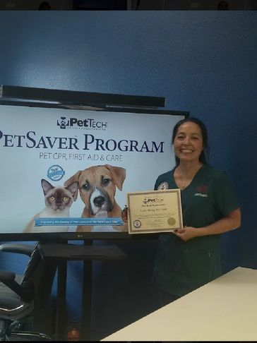 Woman holding a pet CPR certificate in front of a PetSaver Program sign.
