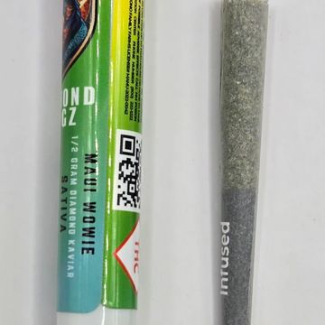 Pre-rolled cannabis joint next to its green and yellow packaging labeled Maui Wowie.