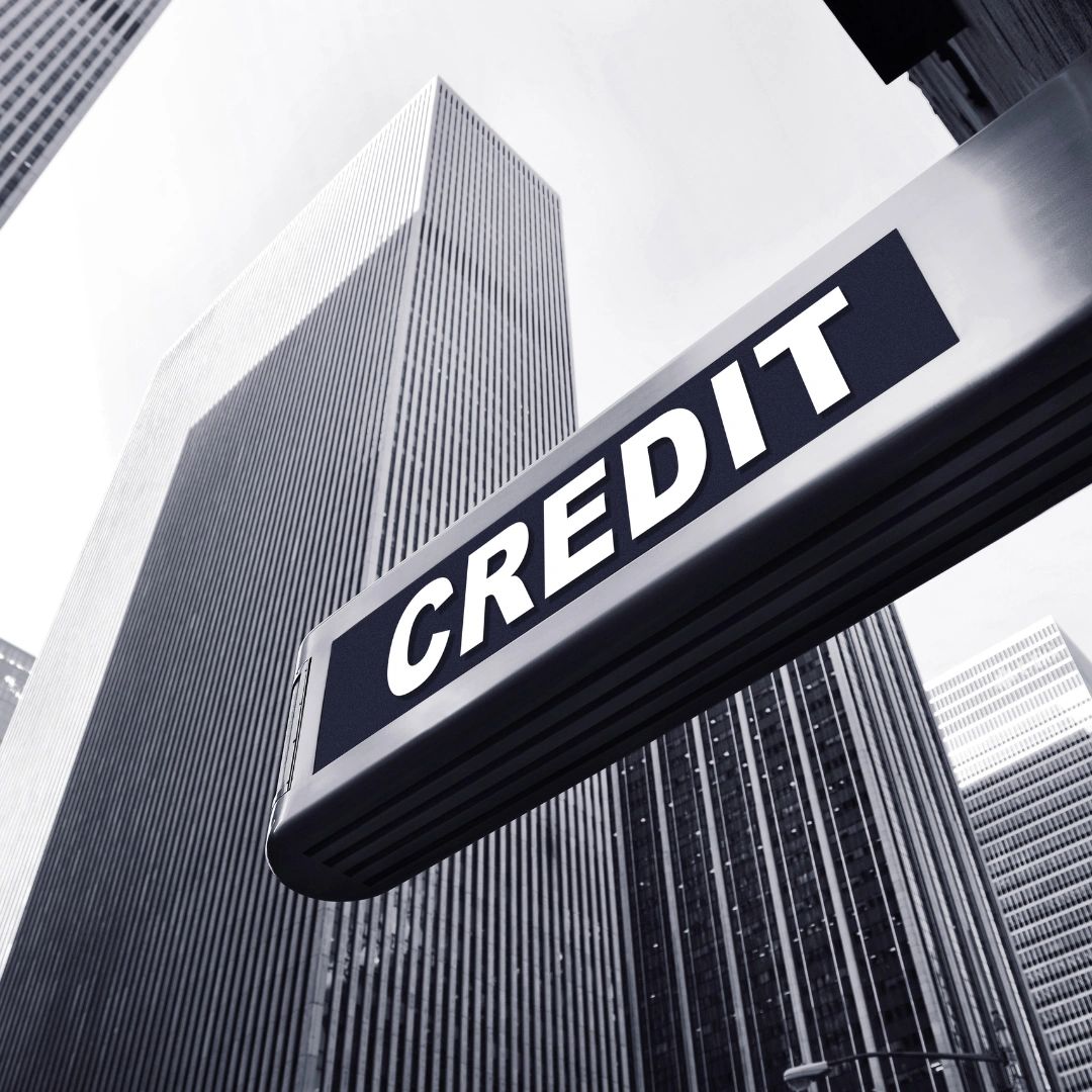 Street sign with 'CREDIT' in front of tall city skyscrapers.