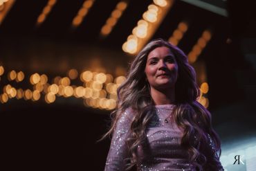 Woman with long hair in a sparkly dress under warm lights.