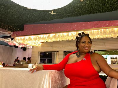 Woman in a red dress seated at a table with a green ceiling.