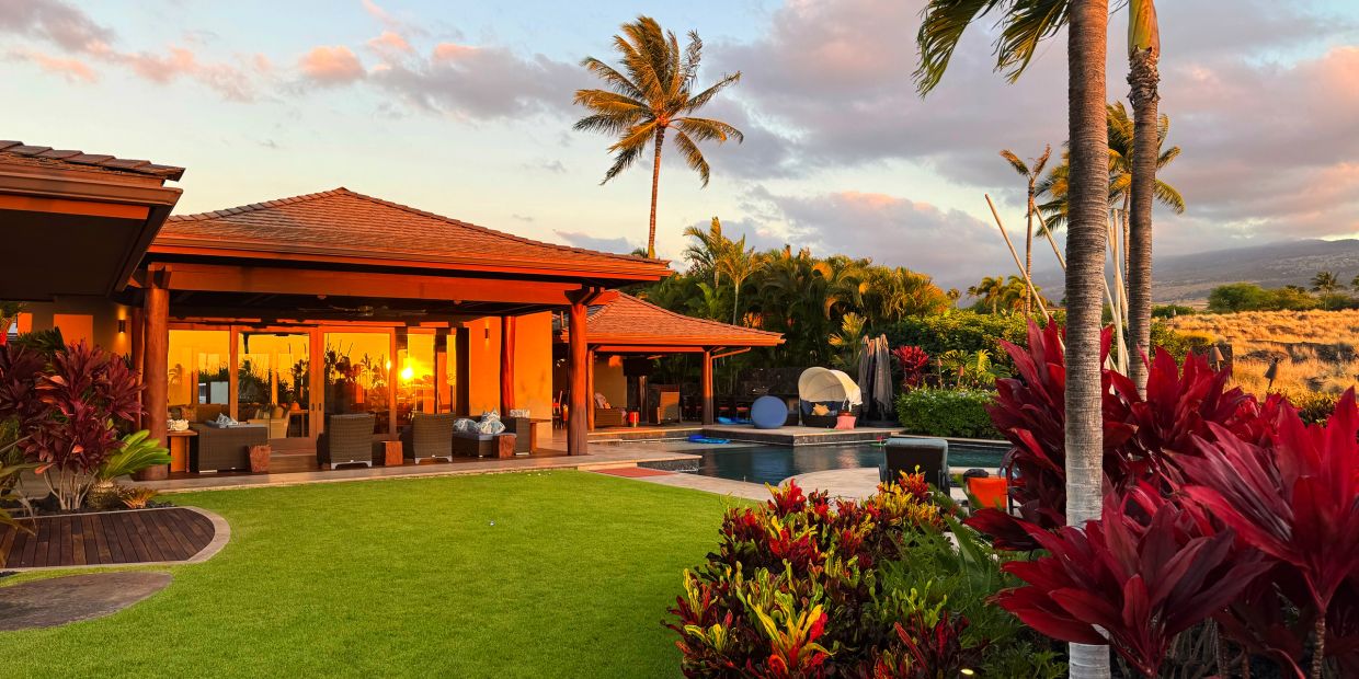Luxury home with garden and pool at sunset.
