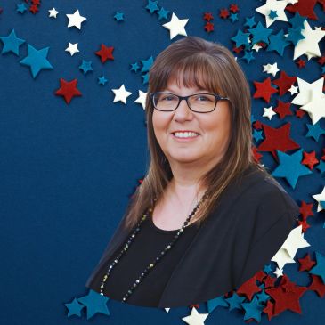 Woman with glasses smiling against a starry background.