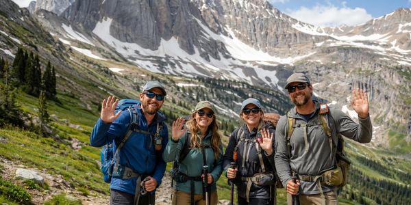 Group of hikers waving in a mountainous area.